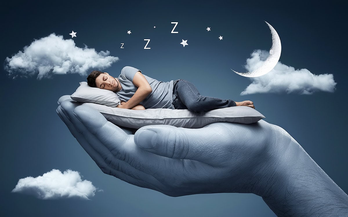 montaje de una mano gigante sobre la que descansa un hombre de lado sobre una cama y de fondo unas nubes, media luna y letras z
